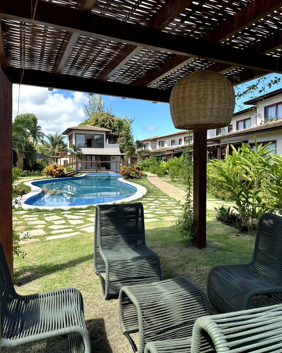 Piscina do condomínio vista da varanda coberta, com espreguiçadeiras e jardim