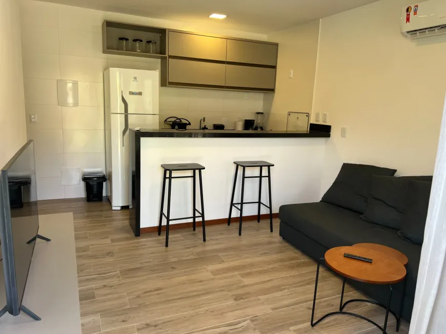 Sala com sofá, TV e cozinha americana integrada
